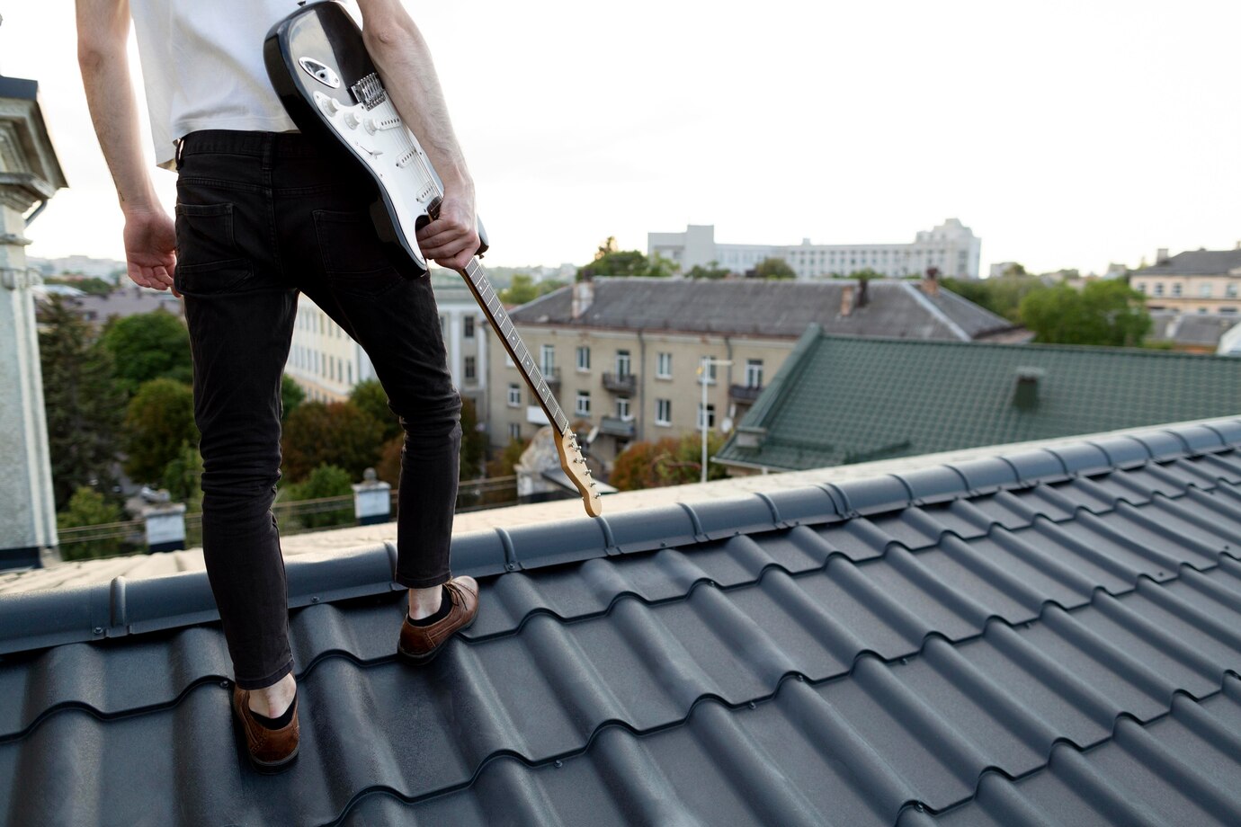 back-view-male-musician-roof-top-holding-electric-guitar_23-2148680355